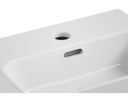 Detailní pohled na bílé keramické umyvadlo s otvorem pro kohoutek a přepadem