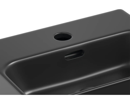 Detailní pohled na černé umyvadlo s otvorem pro vodovodní baterii a přepadem