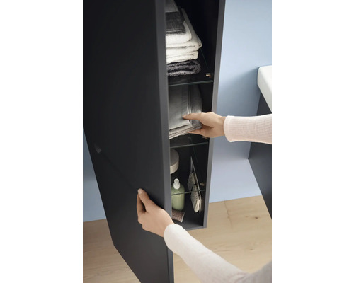 Osoba otevírá koupelnovou skříňku s ručníky a toaletními potřebami na skleněných policích