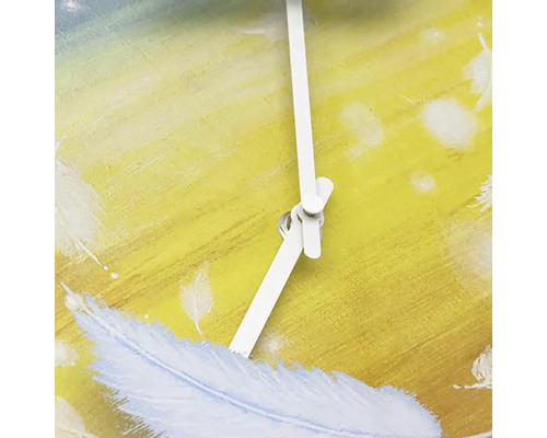 Detail nástěnných hodin s designem peří a bílými ručičkami.