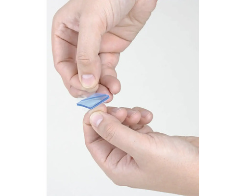 Ruce drží průhlednou obdélníkovou lepicí podložku