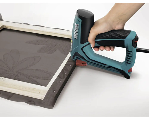 Ruka používá elektrickou sešívačku k připevnění látky na rám