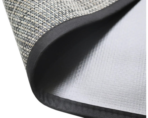 Detailní pohled na prostírání s tkaným povrchem a látkovým okrajem