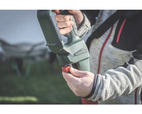 Detailní záběr osoby obsluhující zahradní nářadí s nastavitelnou rukojetí