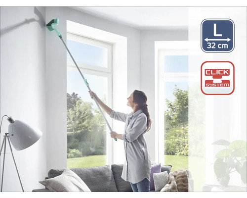 Žena čistí roh stropním kartáčem na teleskopické tyči v obývacím pokoji