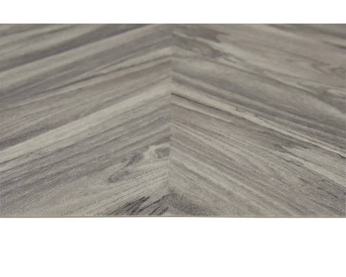 Detail vinylové podlahy ve vzoru rybí kosti s vzhledem dřeva.