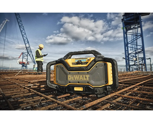 Stavební rádio DeWalt na staveništi se stavebním dělníkem a jeřábem v pozadí