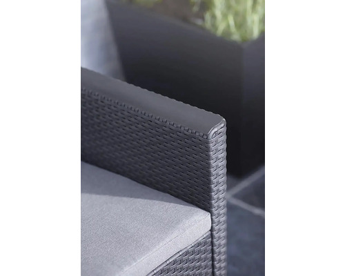 Detailní záběr zahradní židle s šedým polštářem a ratanovým pletivem.