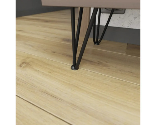 Detail tří černých nábytkových nohou na dřevěné podlaze