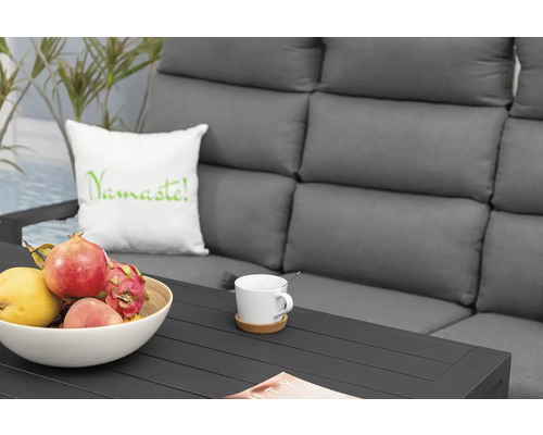 Scéna s pohovkou, šálkem kávy, mísou s ovocem a polštářem s nápisem Namaste