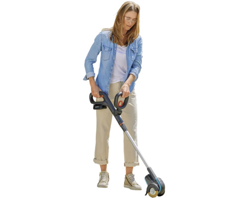 Žena používá akumulátorový čistič spár na zahradě.