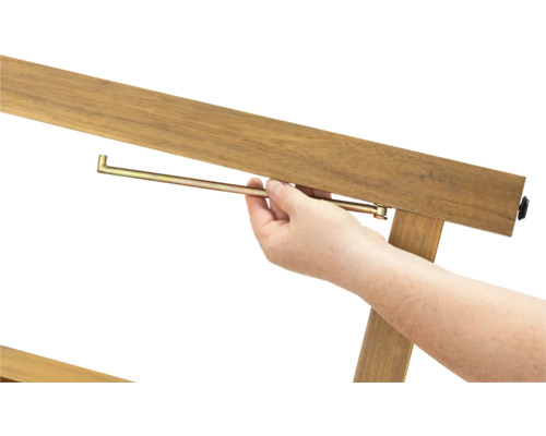 Detailní záběr osoby vkládající kovový kolík do dřevěného rámu