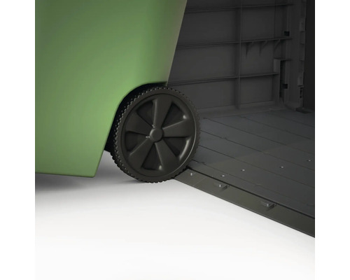 Detailní záběr zeleného kontejneru na odpad s kolečky stojícího v šedém zahradním domku