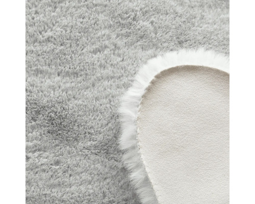 Detail kulatého světle šedého koberce s dlouhým vlasem