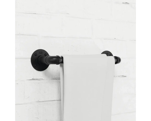 Držák na ručníky z kovové trubky s ručníkem na cihlové zdi