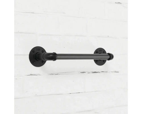 Černý kovový držák toaletního papíru v industriálním stylu na cihlové zdi