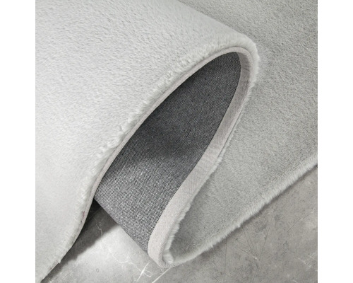 Detailní pohled na koberec světlé barvy s měkkým povrchem a tkanou zadní stranou