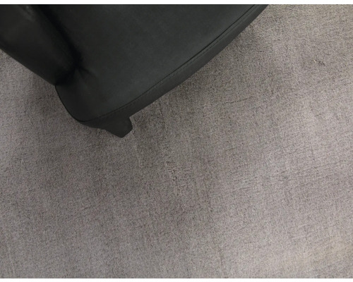 Detailní záběr černého křesla na šedém koberci