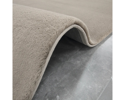 Detailní pohled na béžový koberec s vysokým vlasem.