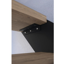 Detailní pohled na upevnění schodiště s dřevěnými stupni a černým kovovým držákem.
