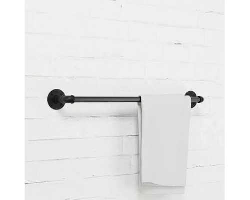 Držák na ručníky z kovové trubky s ručníkem na cihlové zdi