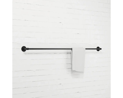 Černý držák na ručníky s ručníkem na bílé zdi