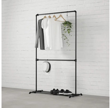 Černý kovový věšák na oblečení s oblečením, kloboukem, botami a rostlinou