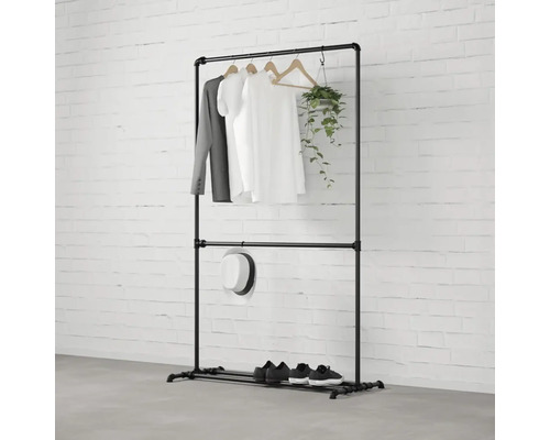 Černý kovový věšák na oblečení s oblečením, kloboukem, botami a rostlinou