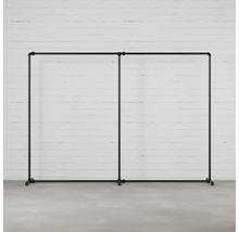 Dvojitý věšák na šaty z trubek před cihlovou zdí