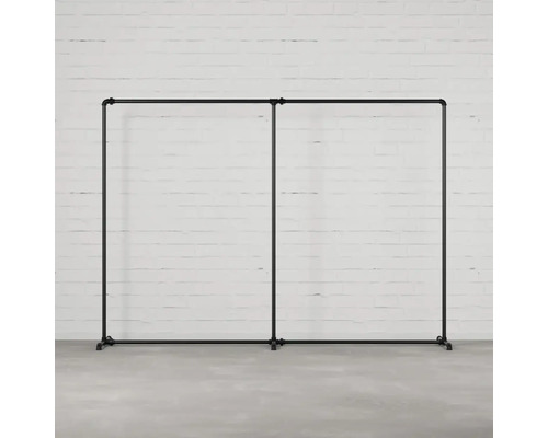 Dvojitý věšák na šaty z trubek před cihlovou zdí