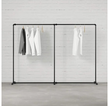 Černý věšák na oblečení s oblečením visícím před cihlovou zdí