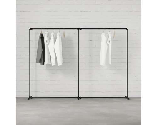 Černý věšák na oblečení s oblečením visícím před cihlovou zdí