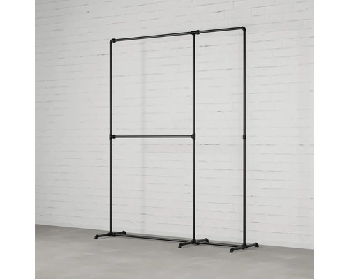 Věšák na šaty z trubek před cihlovou zdí