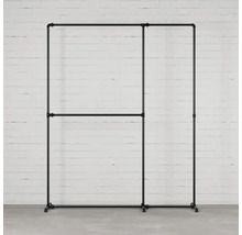 Stojan na oblečení z kovových trubek před bílou cihlovou zdí