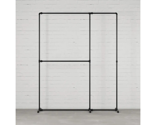 Stojan na oblečení z kovových trubek před bílou cihlovou zdí