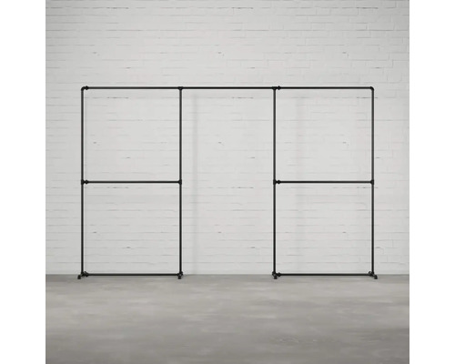 Černá, modulární šatní skříň se stojanem na oděvy z kovových trubek na pozadí bílé cihlové zdi.