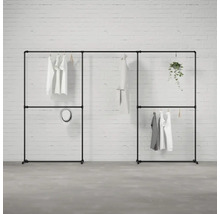 Černý modulární šatní systém s oblečením a dekorací před cihlovou zdí