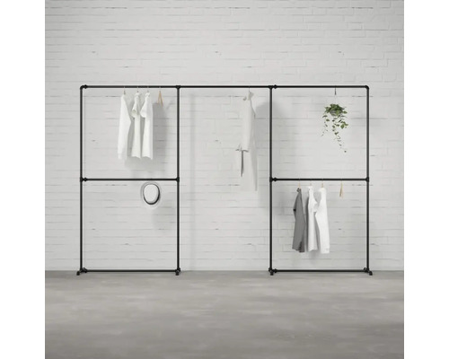 Černý modulární šatní systém s oblečením a dekorací před cihlovou zdí