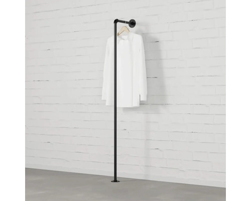 Černý kovový věšák na oblečení s košilí připevněnou ke zdi.