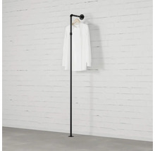 Černá tyč na oblečení z trubek před cihlovou zdí s košilí.