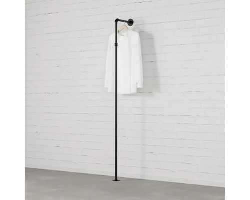 Černá tyč na oblečení z trubek před cihlovou zdí s košilí.