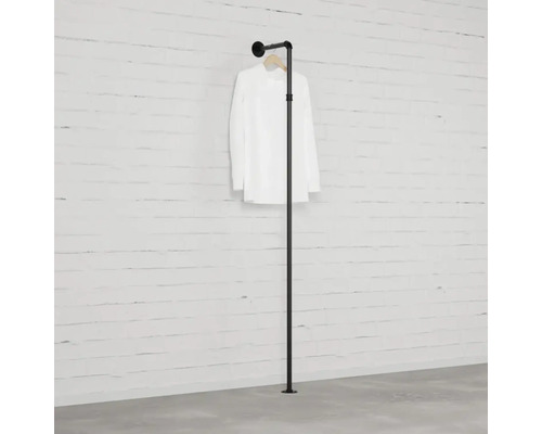 Černý stojan na oblečení s košilí u zdi