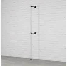 Černý kovový věšák na šaty z trubek u bílé cihlové zdi