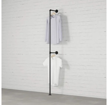 Železný trubkový věšák na šaty se dvěma košilemi visícími před bílou cihlovou zdí