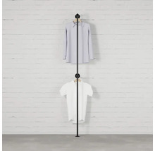 Černý věšák na oblečení se dvěma kusy oblečení před cihlovou zdí