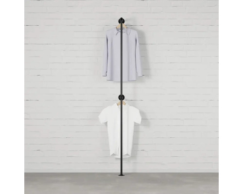 Černý věšák na oblečení se dvěma kusy oblečení před cihlovou zdí