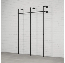 Nástěnný věšák na oblečení z trubek před cihlovou stěnou