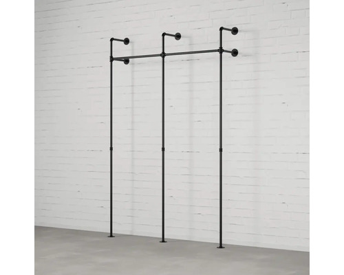 Nástěnný věšák na oblečení z trubek před cihlovou stěnou