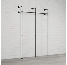 Nástěnná šatna z trubek před cihlovou zdí