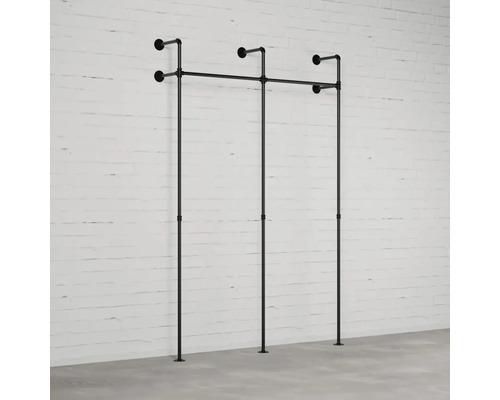 Nástěnná šatna z trubek před cihlovou zdí